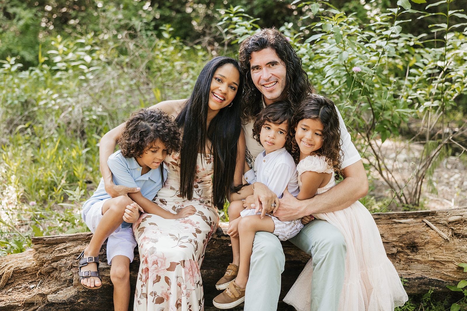 The Santucci family sitting together on a fallen tree in the woods